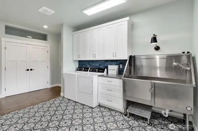 Extra-large laundry & mudroom comes complete with your own dog washing station! Behind the doors straight ahead is a large area for all your extra storage. Notice the opening above storage area that was designed to add extra storage space during the construction phase as an added element. To the right around the corner leads you to the garage.