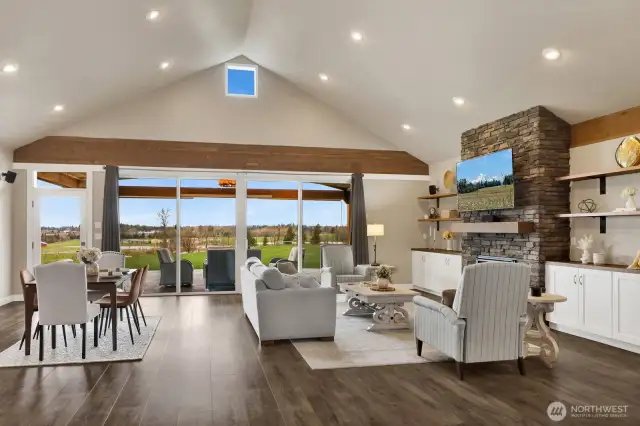 A closer view of the living and dining areas showcasing the 15' vaulted ceilings. Perfect for any gathering, the intended wall of sliders can't help but invite the outdoors in!