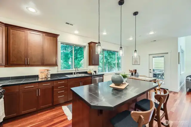 Sleek kitchen with large island / breakfast bar, dining area and door to covered deck.
