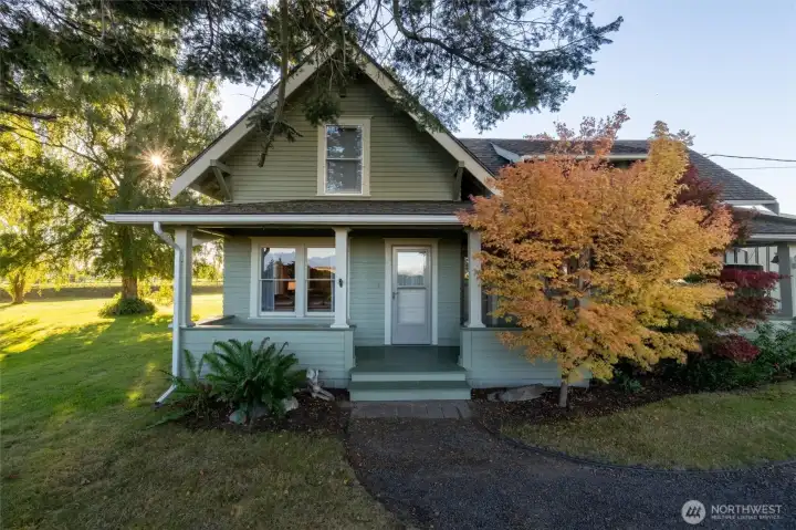 Spacious covered front porch a bit hidden with the colorful foliage.Another door just to right is entrance to the kitchen.