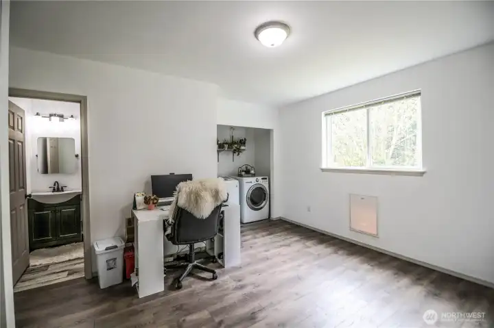 Lower-level family room/bonus rm with LVP flooring, large window, and convenient laundry area.