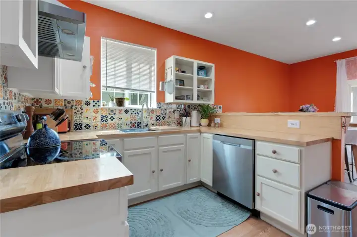 Gorgeous European style kitchen with butcher block counters, hand painted terra-cotta style back splash and stainless steel appliances.