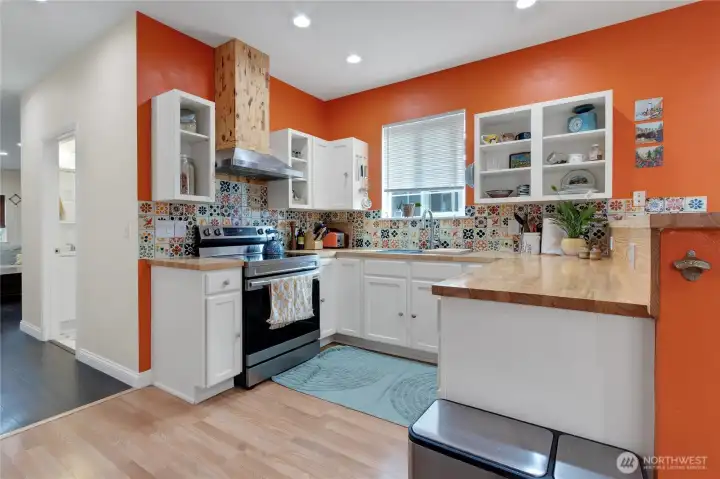 Natural wood wrapped hood chase, open shelving and plenty of lighting make cooking meals fun and exciting!