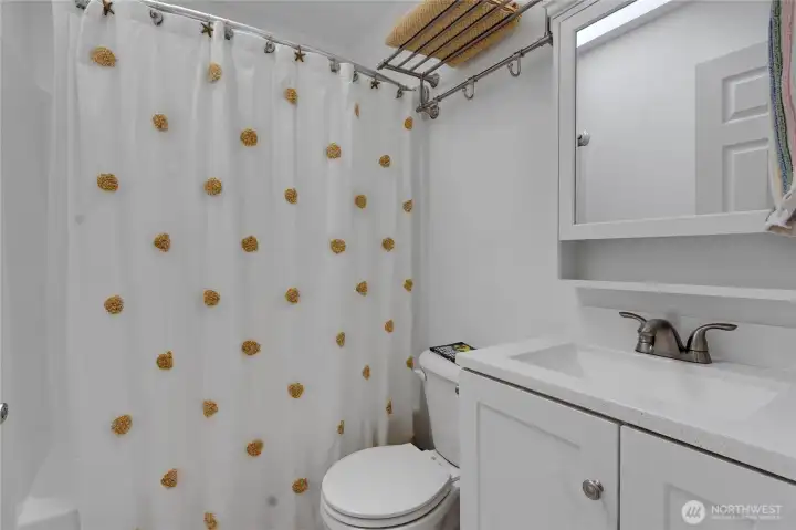 Full guest bath down the hall in between bedroom 2 and the primary bedroom offers new vanity, new mirror/cabinet and an easy to clean tub surround!