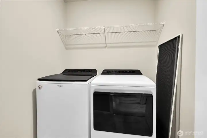 Spacious laundry room with shelving for storage.