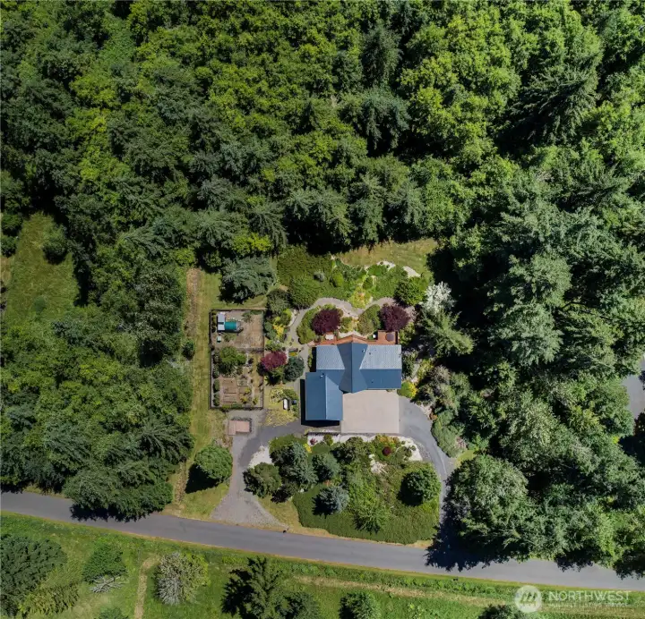 Aerial view shows the house in relation to the garden and chicken area. The whole property has been masterfully landscaped. Property extends into the woods with trails. Aerial view shows the house in relation to the garden and chicken area. The whole property has been masterfully landscaped. Property extends into the woods with trails.