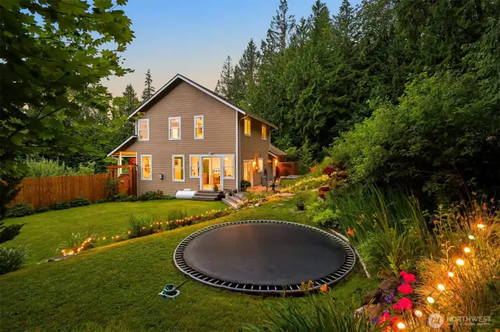The open lawn provides plenty of room for play, gatherings, or simply enjoying the outdoors, all surrounded by gardens and mature forest. The trampoline area sits on the terrace above the main lawn, creating an easy connection between the home and backyard. The open lawn provides plenty of room for play, gatherings, or simply enjoying the outdoors, all surrounded by gardens and mature forest. The trampoline area sits on the terrace above the main lawn, creating an easy connection between the home and backyard.
