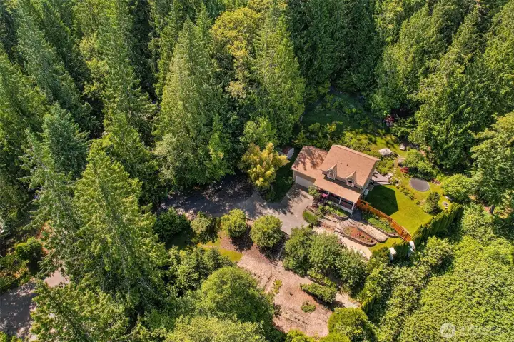 This aerial view helps illustrate how the home, gardens, lawn, and outdoor living spaces are surrounded by a much larger forested setting. The property includes five lots, creating a level of privacy and usable outdoor space that's difficult to find in a typical neighborhood setting. This aerial view helps illustrate how the home, gardens, lawn, and outdoor living spaces are surrounded by a much larger forested setting. The property includes five lots, creating a level of privacy and usable outdoor space that's difficult to find in a typical neighborhood setting.