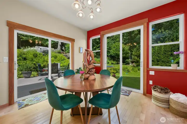 The dining area is wrapped in windows and garden views, creating a bright space that feels connected to the outdoors year-round. Sliding doors on both sides provide easy access to the deck, patio, and surrounding gardens. The dining area is wrapped in windows and garden views, creating a bright space that feels connected to the outdoors year-round. Sliding doors on both sides provide easy access to the deck, patio, and surrounding gardens.