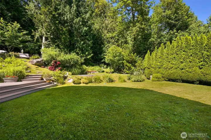 The level lawn provides a rare amount of usable outdoor space, with room for games, gatherings, pets, or simply enjoying the sunshine. Surrounded by gardens, mature landscaping, and forest, it serves as the central open space within the property's larger landscape. The level lawn provides a rare amount of usable outdoor space, with room for games, gatherings, pets, or simply enjoying the sunshine. Surrounded by gardens, mature landscaping, and forest, it serves as the central open space within the property's larger landscape.