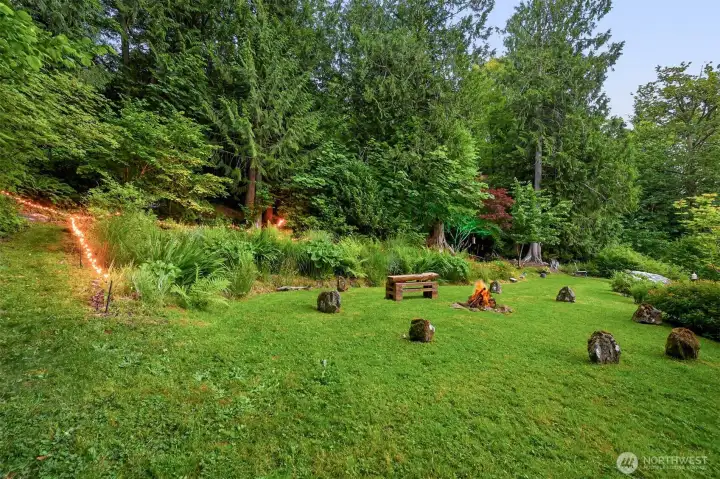 The upper fire pit sits at the edge of the forest and was designed for larger gatherings, with a circular seating area that has become known as "Stonehenge." Connected to the property's trail network and wooded areas, it offers a completely different atmosphere from the lower garden fire pit near the house. The upper fire pit sits at the edge of the forest and was designed for larger gatherings, with a circular seating area that has become known as "Stonehenge." Connected to the property's trail network and wooded areas, it offers a completely different atmosphere from the lower garden fire pit near the house.