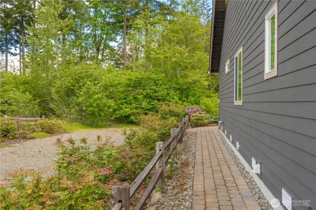 Wonderful hardscape on the West side of the property. Outside the fence is a storm drain easement owned by Pierce County and in partnership with the HOA for maintenance.  Provides extra wide space with no neighbor!