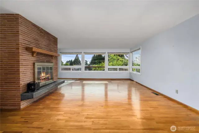 As you enter, you'll notice the wall of windows and original oak floors. Wood-burning fireplace has a gorgeous brick surround.