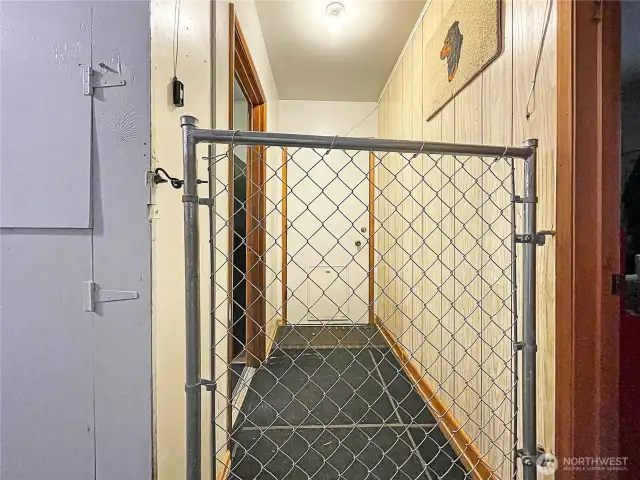 Garage with gate, looking at door to backyard. Extra office room to the right.