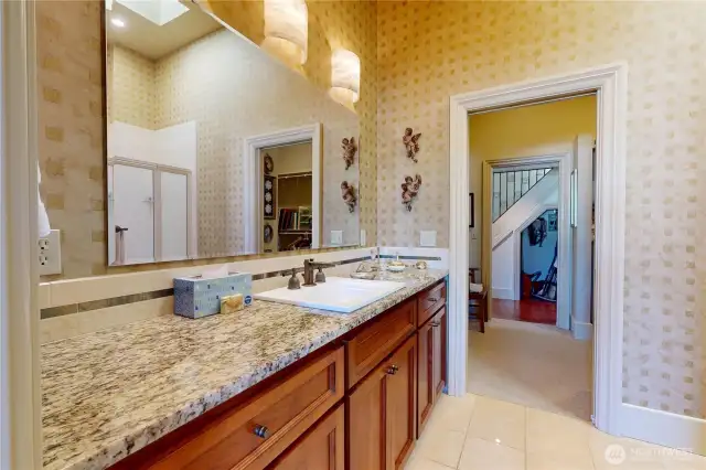 Primary bathroom – granite countertop, wood cabinetry, oversized mirror, and walk-in shower.