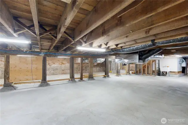 Expansive basement – exposed beams, HVAC, utility sink, and storage areas.