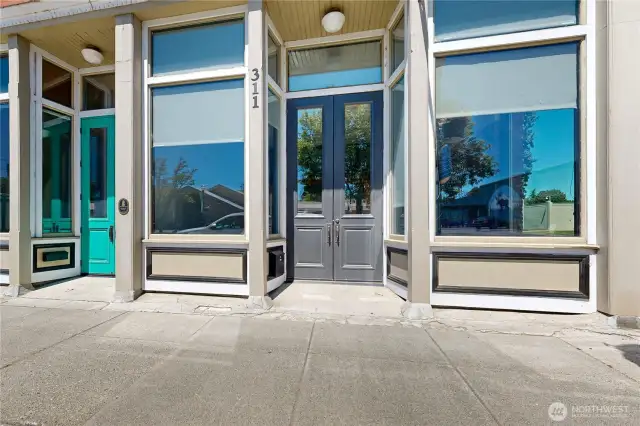 Ample retail spaces with double doors framed by tall storefront bay windows.