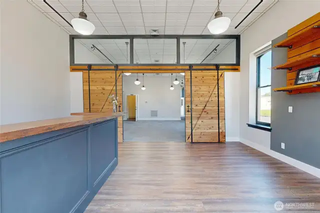 Retail space – very nice setup with wood floors, display shelving, counter, large window, and sliding barn doors. Private restroom at the back.