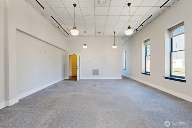 Front left retail space with high ceilings, pendant lights, tall windows with courthouse & street views, and neutral finishes ready for your vision. Private restroom at the back.