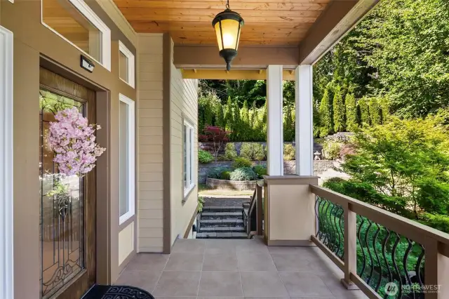 A covered front tiled porch captures a territorial view, with a beautiful terraced garden providing a lush backdrop.