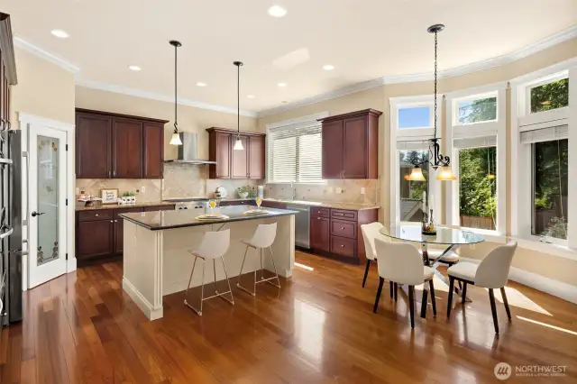 Dream kitchen boasts high-end appliances, including a Bosch refrigerator and dishwasher. Features include a stylish tiled backsplash, glass pantry door, spacious central island with cabinetry, slab granite countertops, and an elegant breakfast nook that flows from the family room to the outdoor retreat. Abundant natural light completes the space.