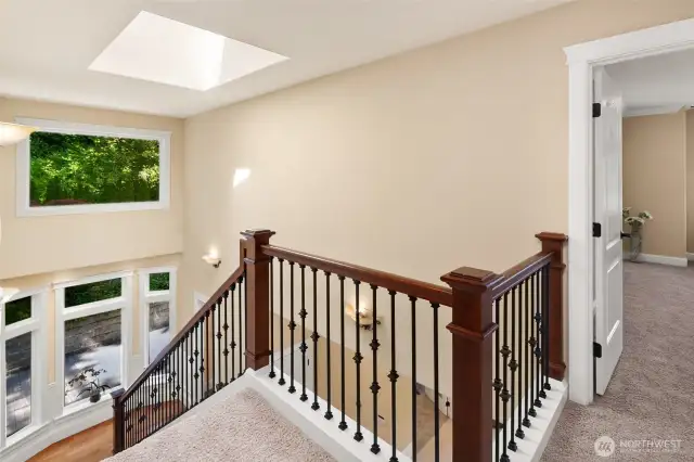 Stunning wrought iron staircase framed by soaring picture windows and a large skylight.