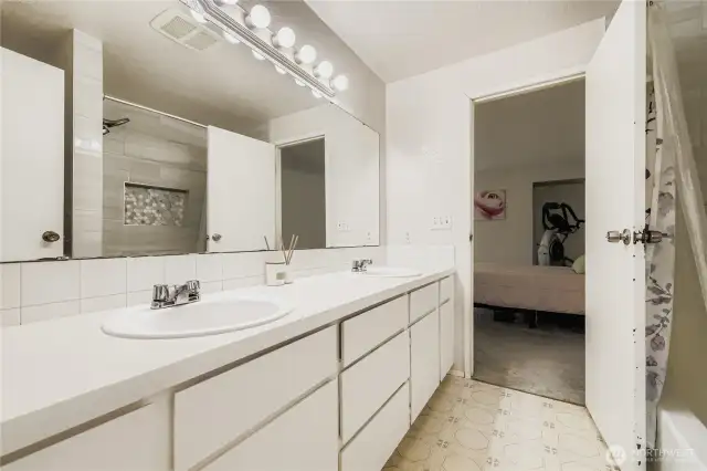 Full upstairs bathrooms with dual sinks, plenty of storage, and updated tile surround bathtub