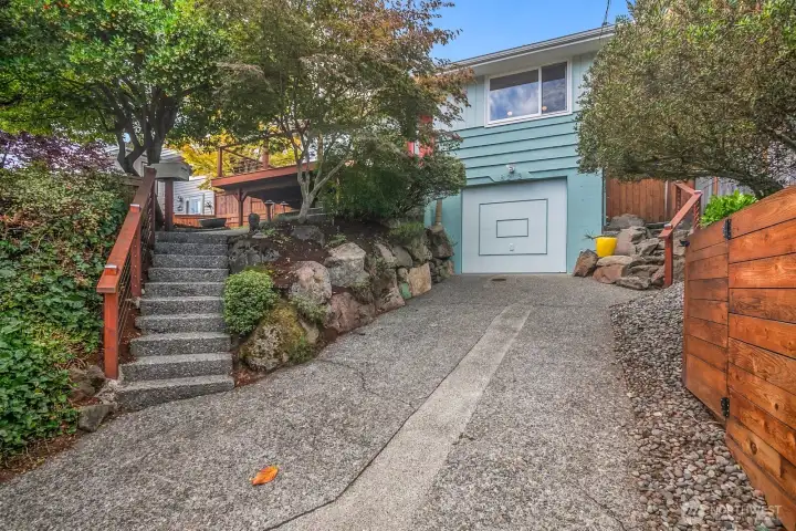 This home sits up from the street and has a 1-car garage and driveway parking.