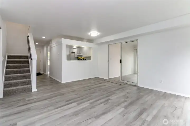 Open living room with stairs that go up to bedrooms and door to sunroom