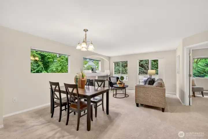 Generous windows wrap the living and dining area in greenery and light, creating a serene, garden-view backdrop for daily life. The seamless layout offers flexible room to dine, unwind, and gather without feeling closed in.