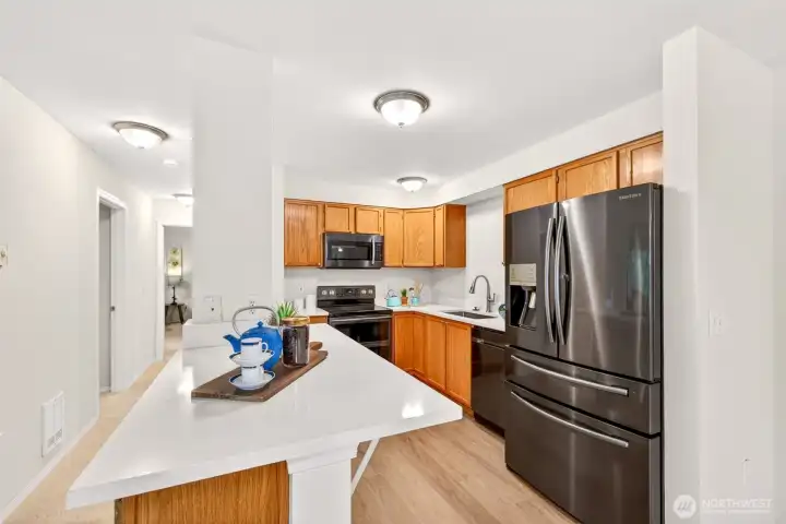 The updated kitchen pairs warm oak cabinetry with new quartz counters and stainless steel appliances, while a generous island anchors the space and invites casual seating and easy prep. Open to the main living areas, it keeps the cook connected to conversation and flow.