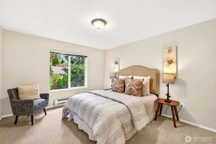 The spacious primary bedroom offers room to truly relax, with a window framing greenery and treetop views. New carpet and a soft, neutral backdrop create a serene, private escape.