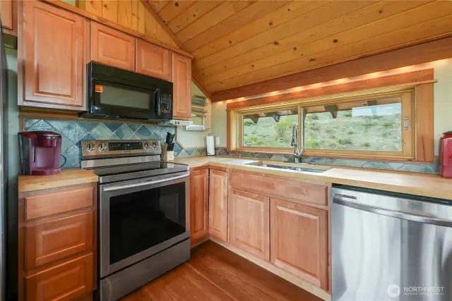 Stainless steel appliances including dishwasher, microwave, and range.  Utility room with washer and dryer downstairs.