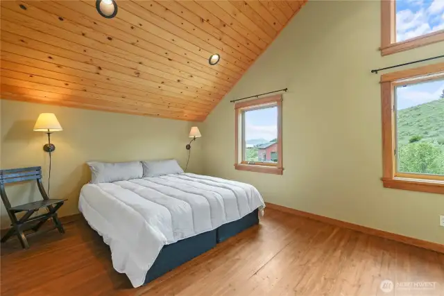 Quiet primary bedroom with vaulted wood ceiling and warm finishes
