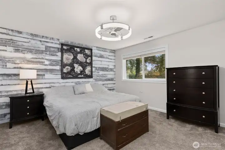 Spacious primary bedroom with modern lighting and ceiling fan