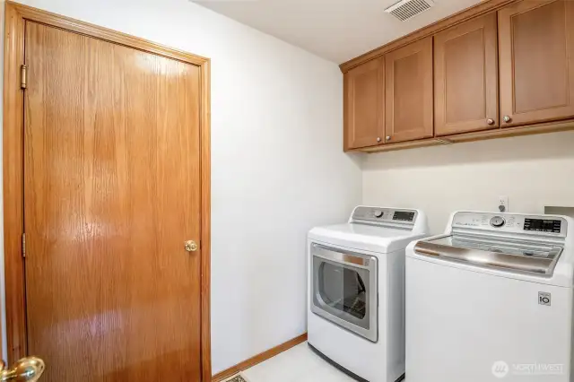 Utility room with storage cabinets with tile floors and door to garage.