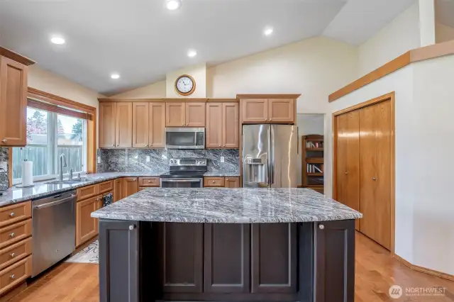 Updated kitchen displays attention to detail with newer cabinets w/extra large island, stunning granite countertops and backsplash, stainless steel appliances, range has double ovens, vaulted ceilings and open shelf above pantry for decor.