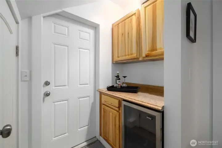 Dry bar with wine/beverage fridge for entertaining  and exit to driveway.