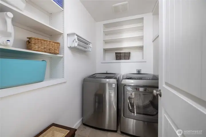 The included washer and dryer are stationed in the laundry room with two walls of storage shelves.