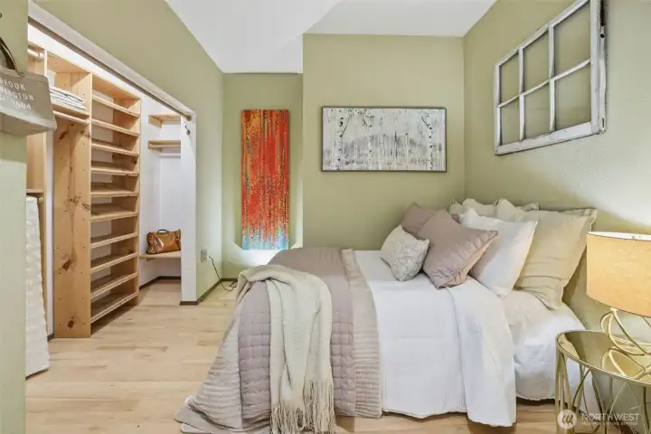 Well-designed bedroom with a built-in closet system that maximizes both storage and function. Custom wood shelving provides dedicated space for shoes, folded items, and accessories, while dual hanging areas keep clothing organized and easy to access. The open layout creates a clean, boutique-style feel and makes daily routines more efficient. Generous capacity without bulky doors keeps the room feeling open and uncluttered.