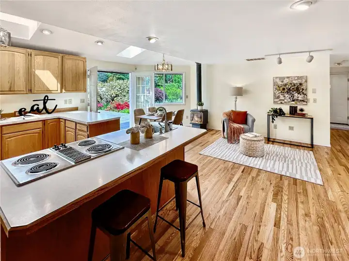 Kitchen with dining area and island features freshly refinished hardwood floors, propane free standing stove and French doors leading to large deck and private rear yard.