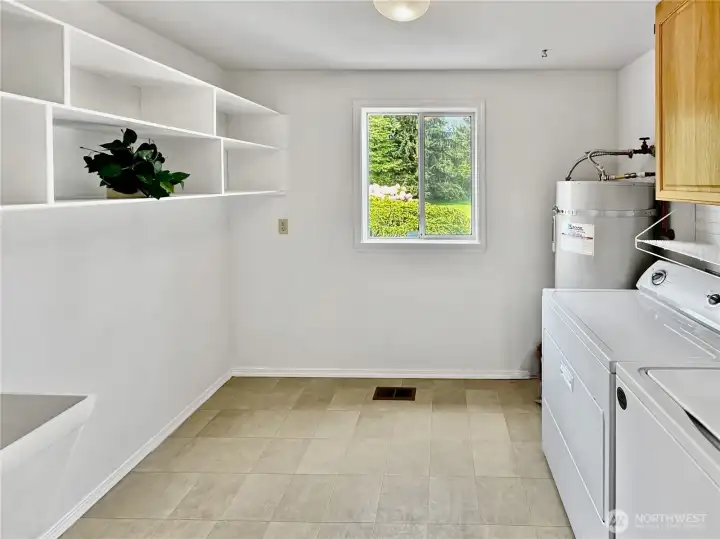 Generous laundry room with utility sink, new flooring and plenty of storage.