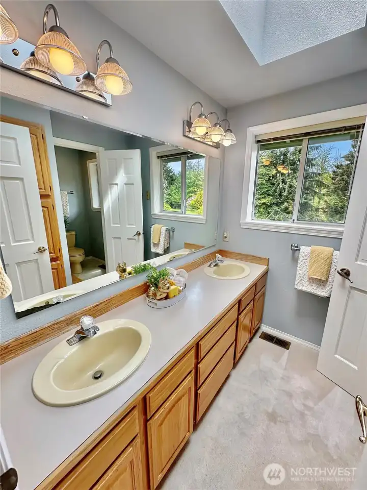 Hall bath with double sinks and separate toilet and shower room.