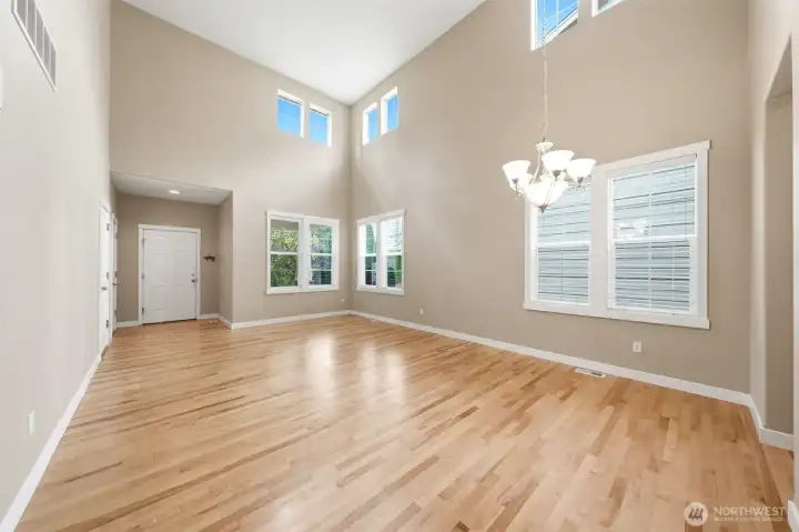 Two story living and dining room with walls of windows.