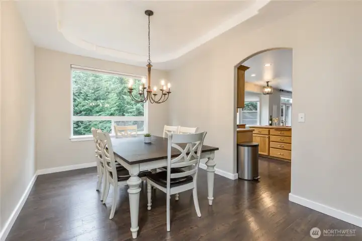 Formal dining room has elegant tray ceiling and curved doorway into the kitchen