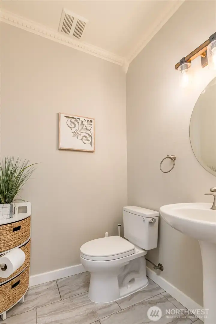 Half bath on the main level features elegant details like crown moulding and beveled oval mirror.