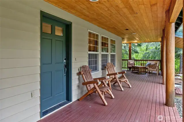 Covered wrap-around porch, elegantly framed by exposed wooden beams.