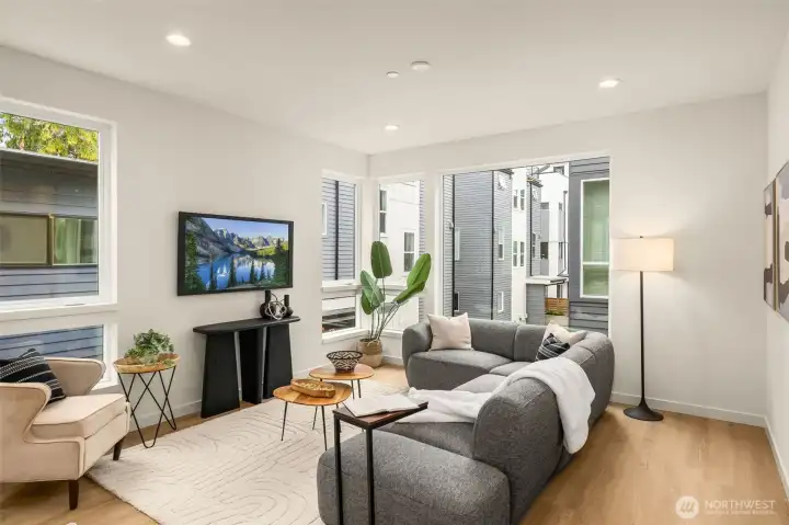 Spacious open-concept living room boasting oversized windows and elegant hardwood flooring