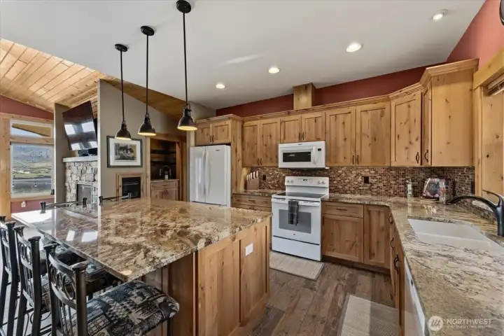Spacious kitchen features hickory cabinetry, oiled bronze hardware, granite countertops, tile backspace, under cabinet lighting and a generous island w/ room for seating and entertaining.
