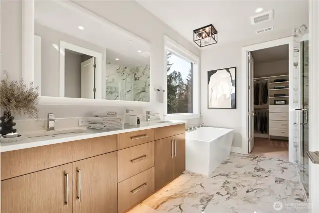 Primary bath with dual sinks, soaking tub and tiled walk in shower.  Built in closet is beyond